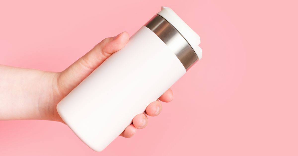 Pink background with a person holding a thermos