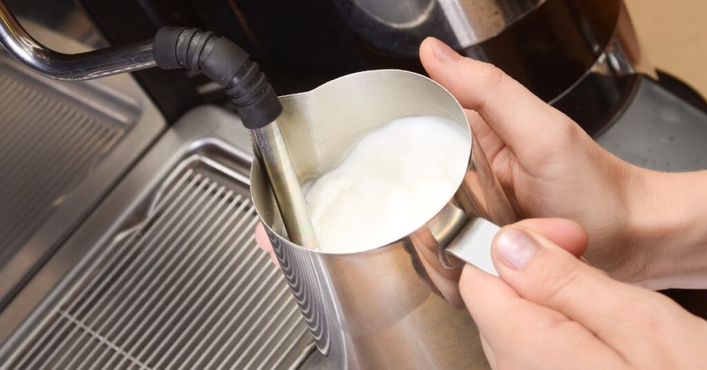 Flat White vs Cappuccino - Person Frothing Milk on a coffee machine