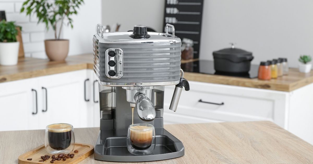 A coffee machine on a table with a cup of coffee and some beans next to it