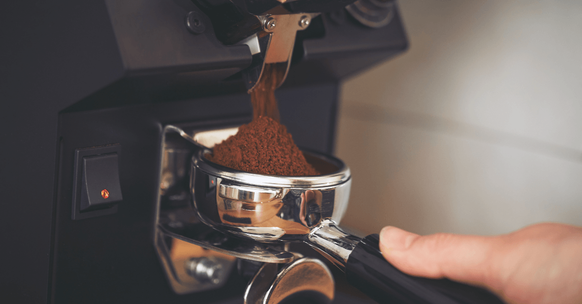 Person grinding coffee into a coffee tamp