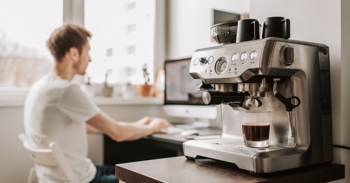 man sitting at his desk with a focus view on his coffee machine